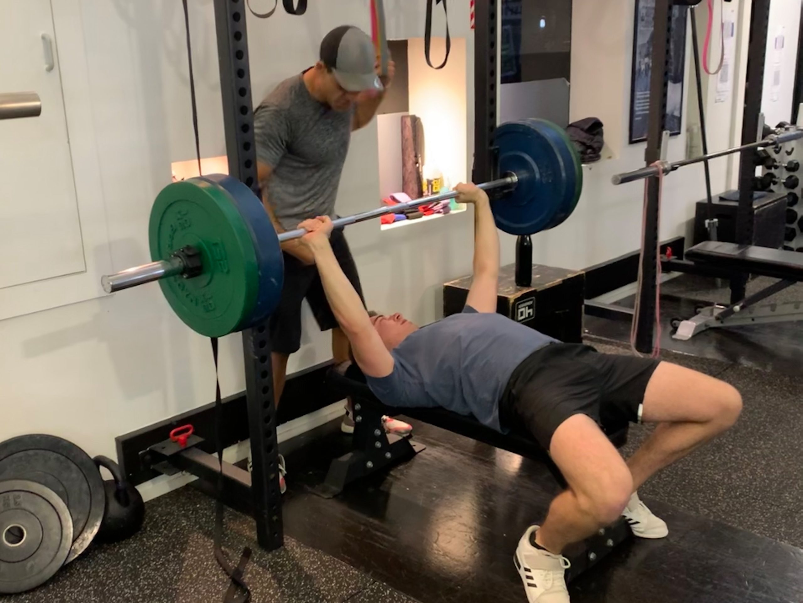 Personal trainer Phil Chapman spotting a midlife man performing a bench press at Body Torque Gym in Newmarket.