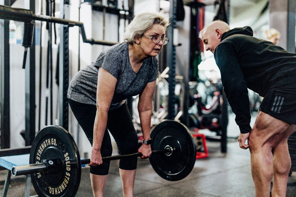 Mid-life woman in activewear performing a deadlift at Body Torque Gym in Newmarket with personal trainer Alex Flint.
