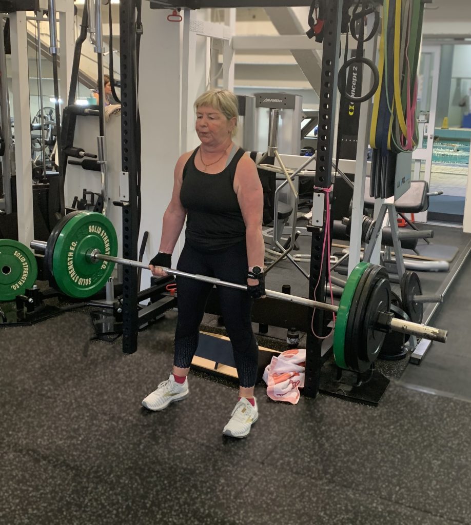 Woman over 60 performing a barbell deadlift at Body Torque Gym in Newmarket Auckland